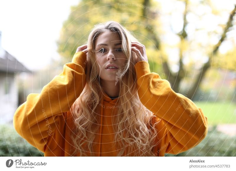 Portrait of a young, slim woman with long blond hair and yellow hoodie on the balcony in autumn Woman Young woman Large Blonde Long-haired pretty daintily Slim