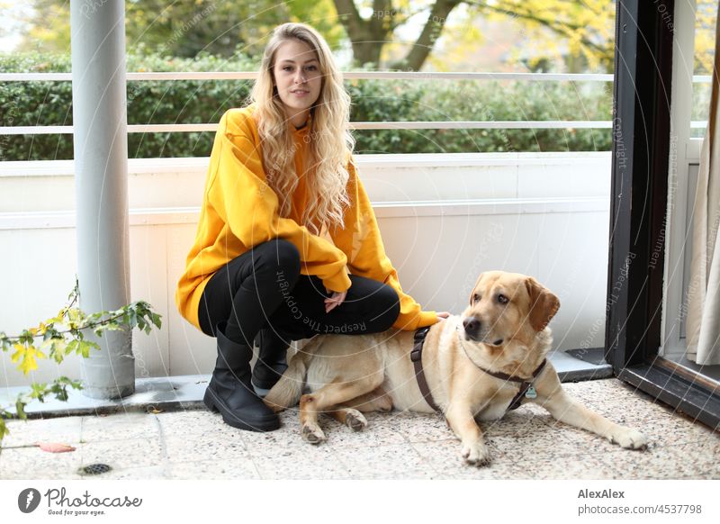Young tall blonde slim woman squats next to blonde labrador on balcony Woman Young woman Large Blonde Long-haired pretty daintily Slim athletic Esthetic