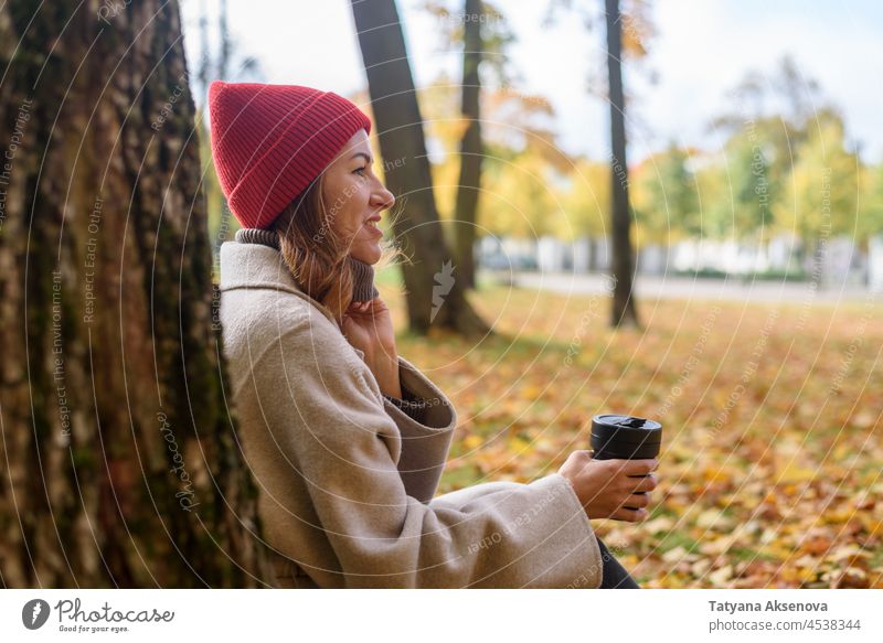 Woman drinking from reusable cup at autumn park woman fall environmental conservation female adult lifestyle person outdoor nature mug one person relaxation