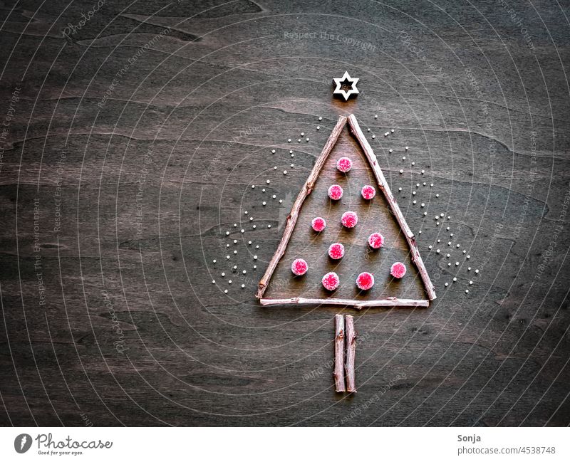 Ein Christbaum aus Ästen und kleinen roten Kugeln auf einem Holztisch Weihnachten Weihnachtsbaum Advent Winter Ast kugel basteln holztisch abstrakt draufsicht