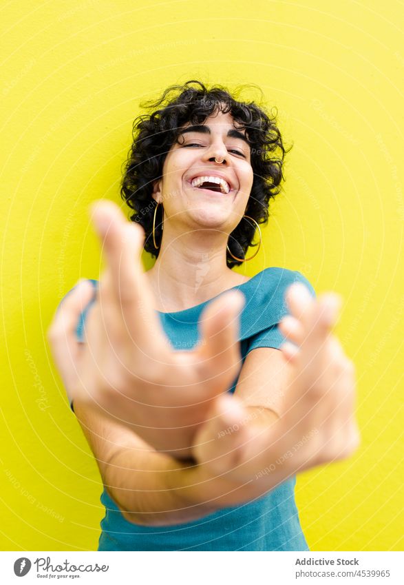 Happy woman reaching crossed hands to camera laugh joy fun bright cheerful expressive colorful happy carefree female optimist positive glad smile curly hair