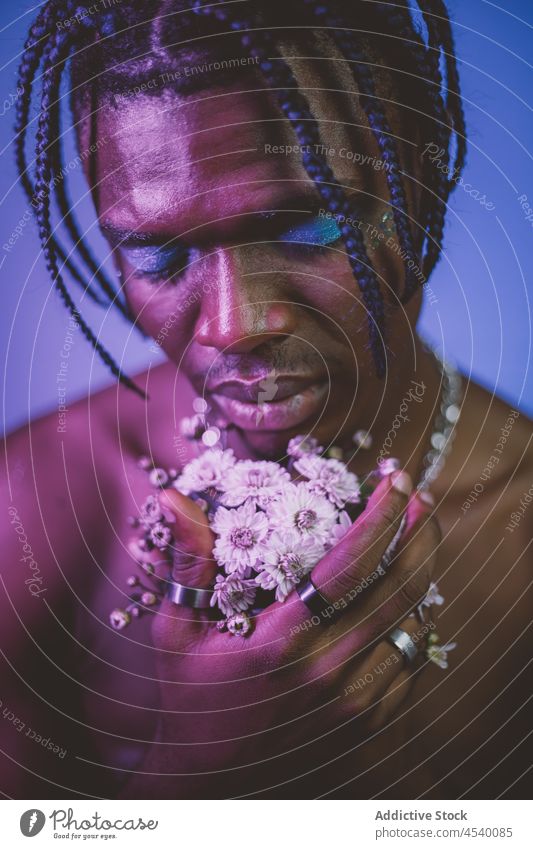 Serious shirtless black man with makeup and flowers alternative provocative eccentric appearance bouquet extravagant informal floral plant unusual naked torso