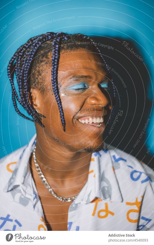 Smiling black man with makeup alternative style appearance eccentric fashion extravagant informal unusual confident hairstyle braid male african american