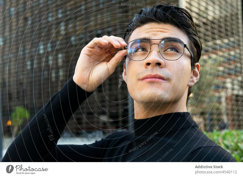 Asian man in eyeglasses on street building city style urban modern appearance respectable outfit asian ethnic apparel trendy guy male contemporary wear adjust