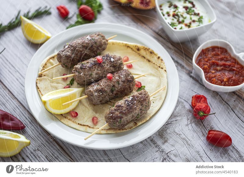 Traditional homemade kafta or kofta kebab with tomato sauce and yoghurt lamb kefta skewers spices halal food background Turkish food Arabic food meat Moroccan