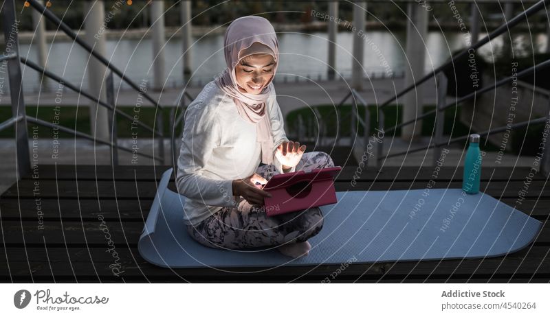 Arab woman browsing tablet on waterfront in evening time stair online embankment hijab river leisure pastime riverside shore female surfing cellphone arab
