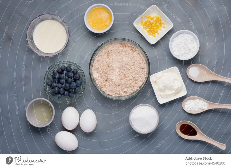 Set of ingredients in bowls and spoons for cooking muffins recipe blueberry flour composition pastry prepare mix milk butter lemon zest sugar salt soda