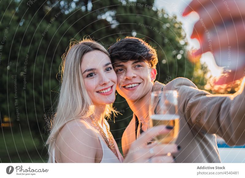 Couple taking a selfie in park couple cheerful alcohol together smartphone cellphone champagne self portrait carefree using chill bonding relax summer gadget