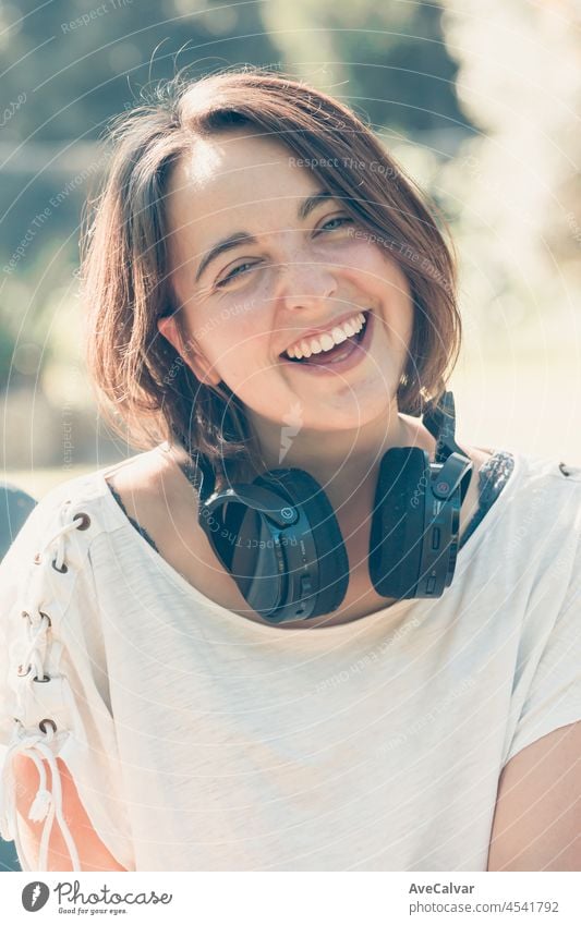 Young woman with short hair having fun while using a big headset to hear music. Outside activities. Happy young girl music enjoy. earphones hipster player