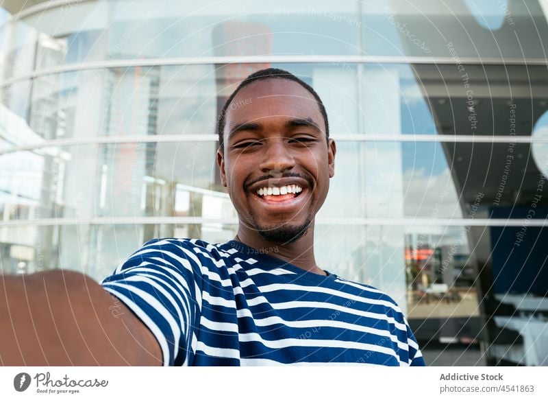 Cheerful black man taking selfie on street self portrait city building capture photography memory modern african american hobby male positive moment cheerful