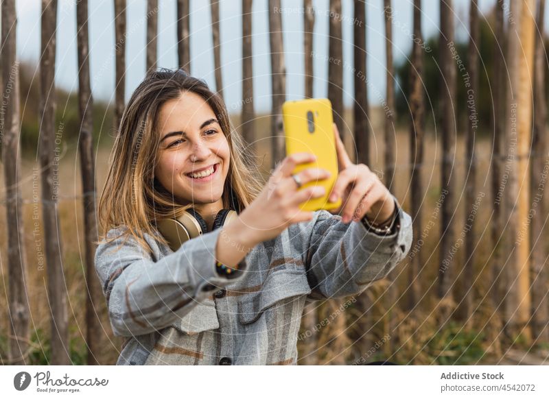 Young lady taking selfie on smartphone witting on wooden path woman countryside boardwalk relax photography take photo nature social media connection mobile