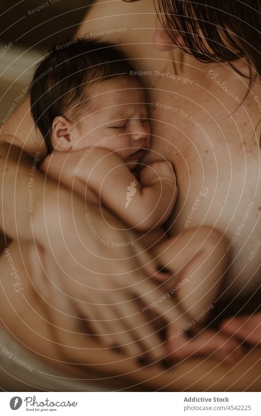 Anonymous mother hugging baby woman embrace newborn breastfeed love naked together motherhood childhood nude female young home cute adorable affection calm mom