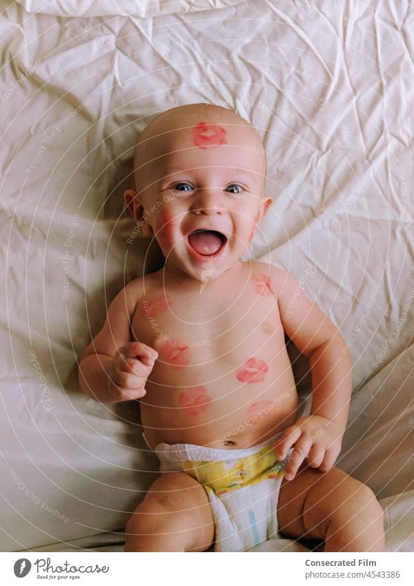 Baby boy laying on bed with lipstick kisses all over him Kisses baby kisses childhood love cute portrait caucasian adorable family lifestyle Lipstick