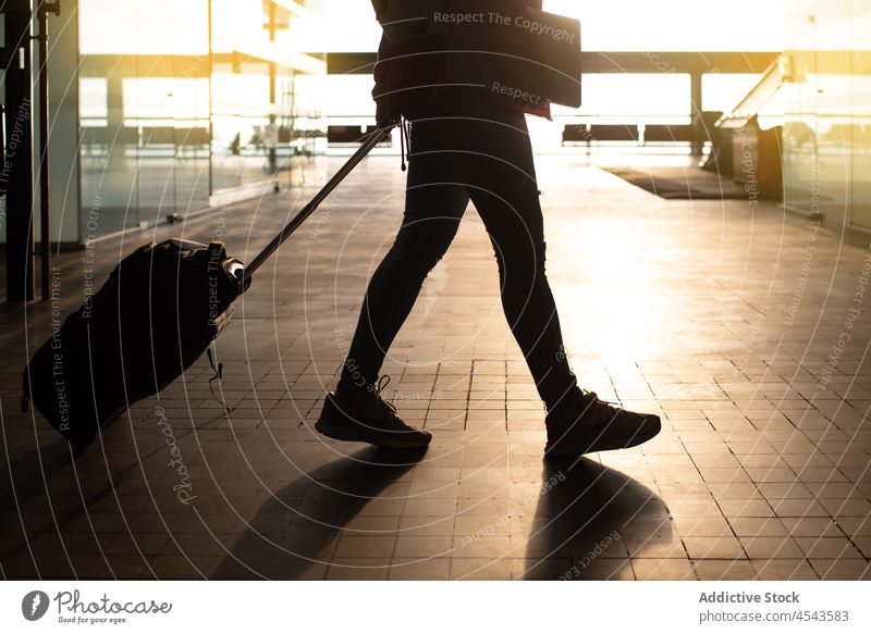 Anonymous passenger walking with luggage in airport suitcase traveler trip modern terminal departure lobby public direction contemporary tourist infrastructure