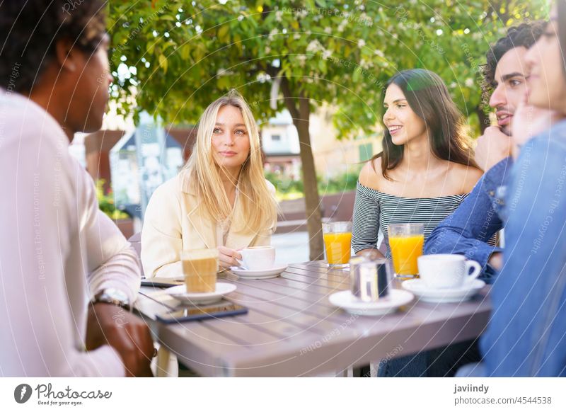 Multi-ethnic group of students having a drink on the terrace of a street bar. people multi-ethnic diversity friends friendship smartphone men women cheerful