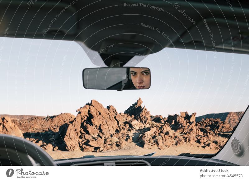 Woman looking at mirror in car in nature woman automobile windshield rocky formation trip adventure road trip driver vehicle female parked stony transport