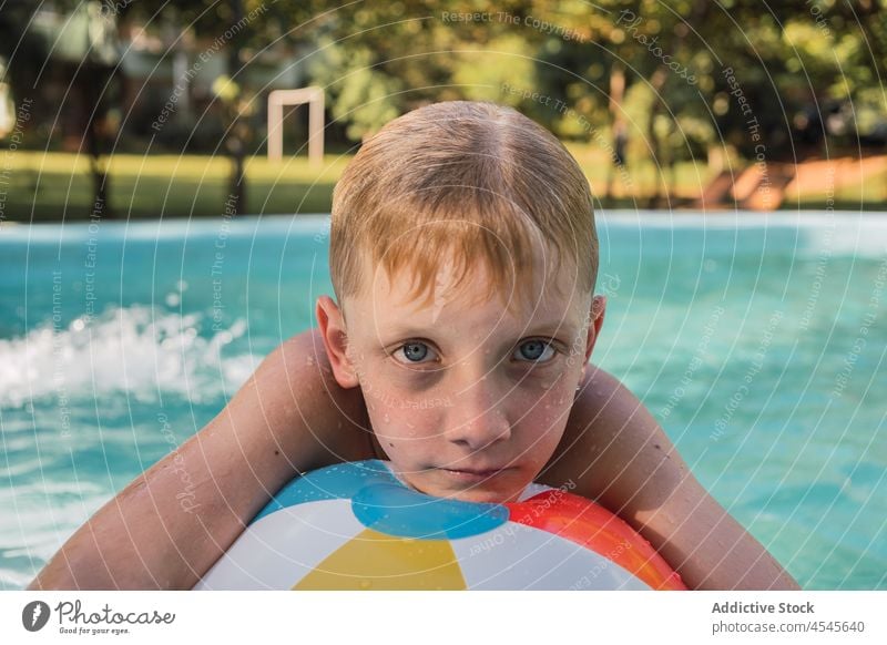 Kid leaning on inflatable ball while swimming in outdoor pool child vacation relax calm holiday boy resort rest weekend kid blond wet hair preteen summer