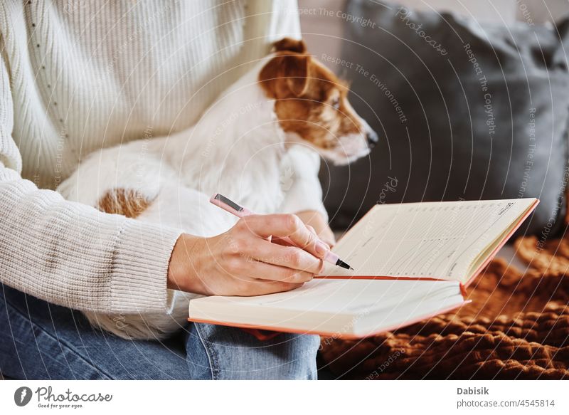 Woman write notes in notebook at home woman dog diary plan lifestyle cozy rest relax office workplace indoors table drawing freelance friendship handwriting