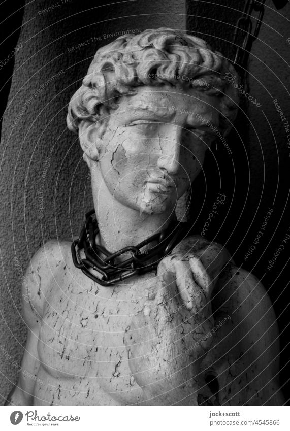No one needs this necklace Statue in chains Ravages of time Weathered Esthetic Backup Young man Paint is off King David idealism Chained up unhappy Precuation