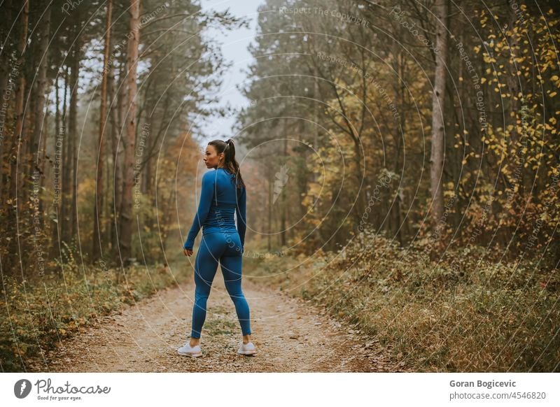 Young woman take a break during outdoor exercise on the forest trail at autumn resting activity adult athlete athletic attractive blue caucasian country