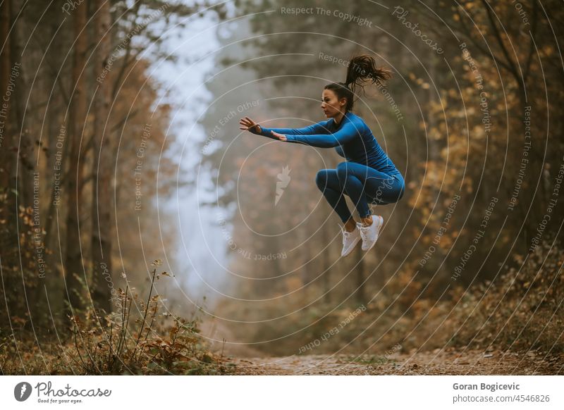 Young woman taking high jump on the forest trail at autumn action active activity adult athlete athletic attractive blue caucasian country endurance energy