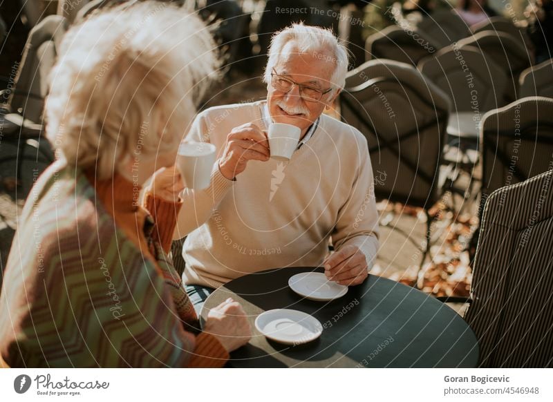 Senior couple drinking coffee in the outdoor cafe on a sunny autumn day caucasian talking man table old people senior woman mature happy female together