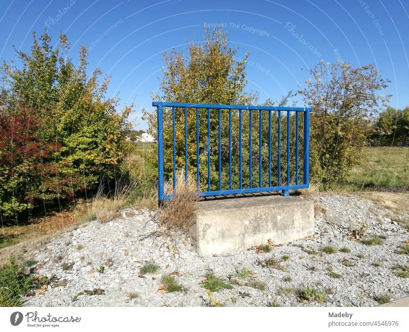 Beautiful blue railing made of steel with foundation made of concrete in the undeveloped nowhere in front of a blue sky with sunshine in Oelde near Warendorf in the Münsterland in Westphalia