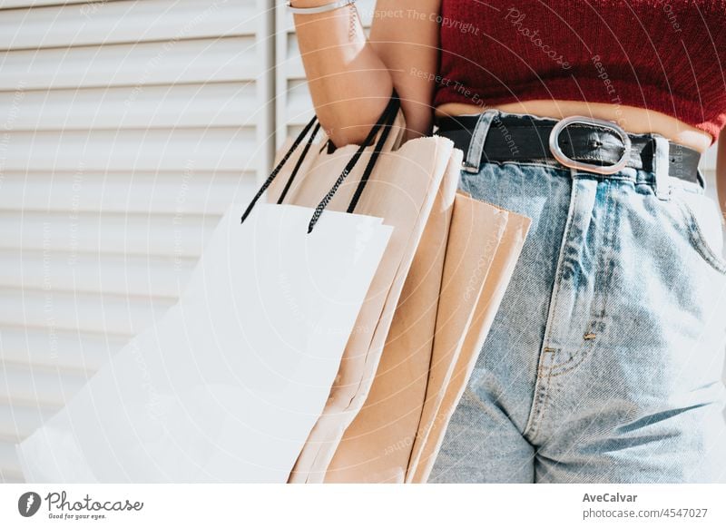 Elegant and modern woman in standing on the city street and holding bunch of shopping bags. Close up shot of woman hand. Lifestyle consumerism theme. person