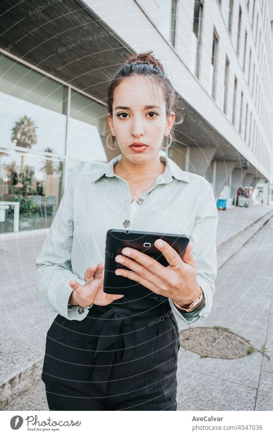 Focused professional using app on tablet outside. Young African American business woman holding digital device, looking at screen, smiling. Online app concept, businesspeople,break from meeting