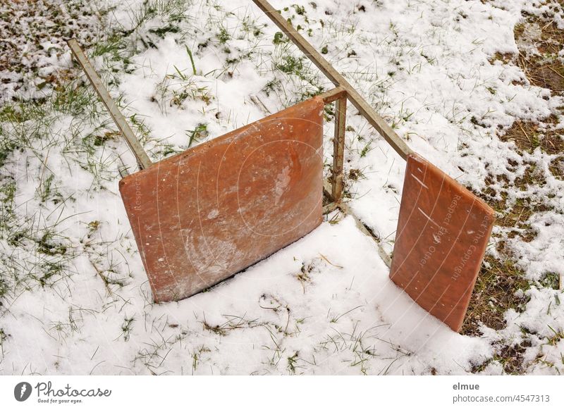 an old kitchen chair / office chair made of a metal frame and brown plastic upholstery lies on the snow-covered meadow / winter / seating furniture Chair Snow