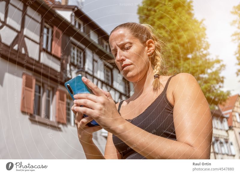 Female using cell phone in city background. Young woman using an app in mobile phone,typing text message on traditional houses background person urban
