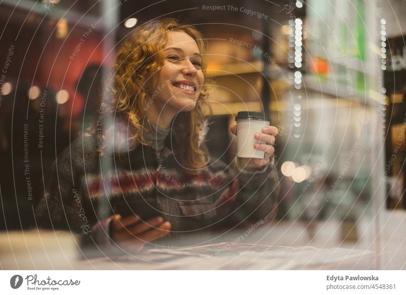Smiling young woman with cup of coffee behind window in a cafe one person adult beautiful casual female girl people lifestyle urban city street attractive town