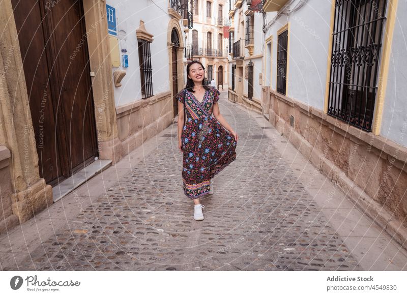 Smiling Asian woman between aged buildings path town travel old tourism street house architecture sightseeing tourist pathway footpath pave residential summer