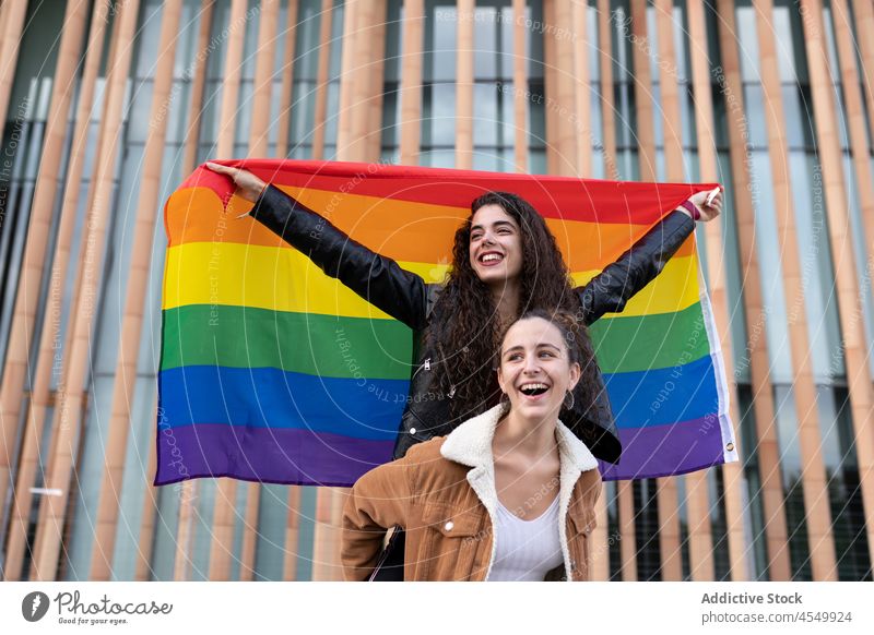 Happy homosexual women with LGBT flag couple lgbt rainbow relationship unconventional lesbian equal solidarity bonding tolerance love street together pride
