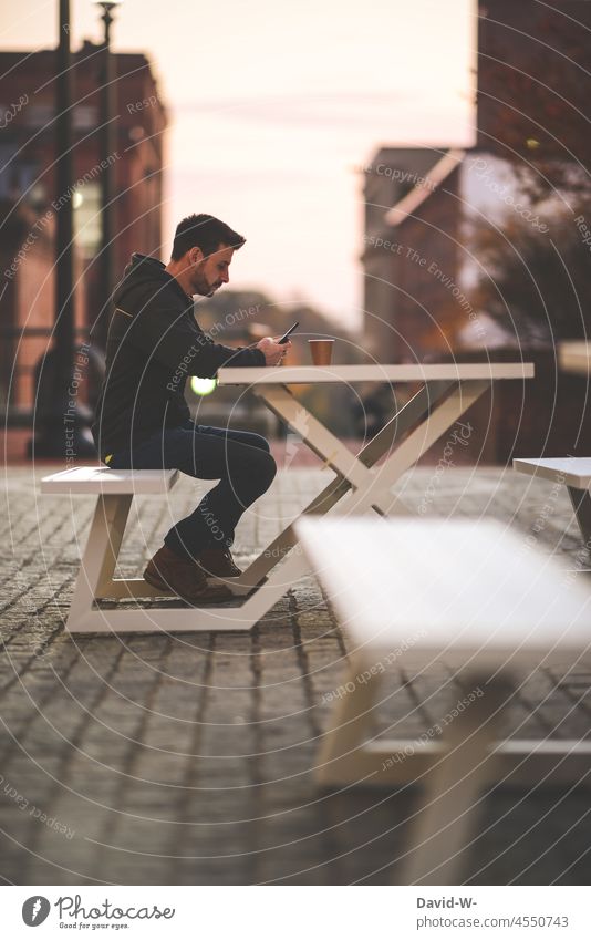 Man sitting outside at a table of a coffee shop using his mobile phone Sit Coffee Cellphone concentrated To have a coffee Coffee break Gastronomy Table Bench