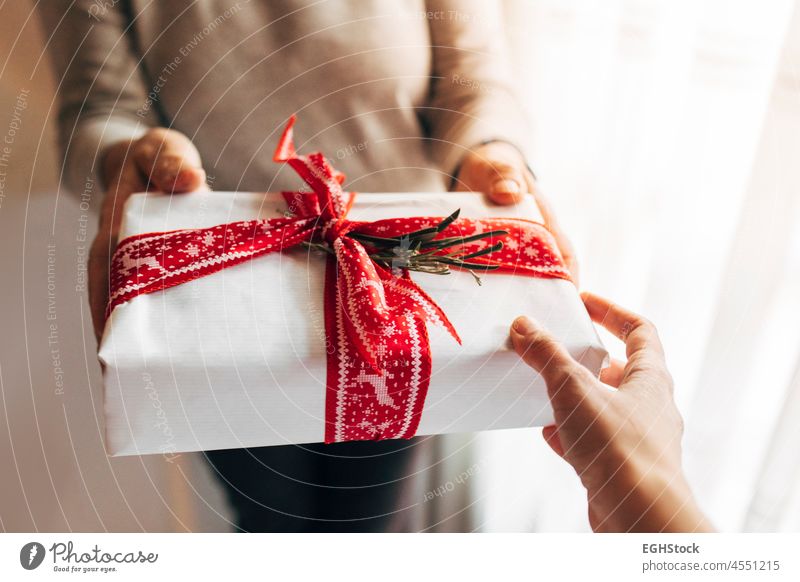 Woman giving christmas gift box with red printed ribbon. Xmas and New Year present, winter holiday. 2022 xmas ornament merry year new santa minimal claus season