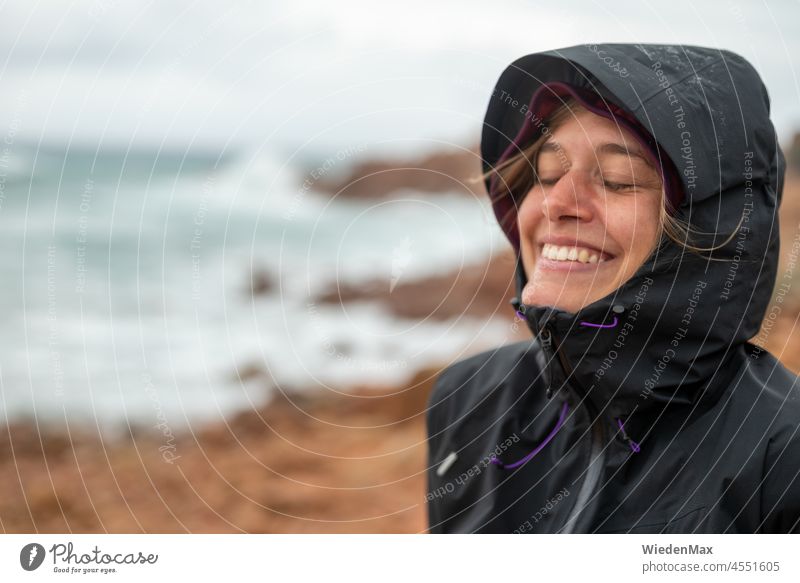 Joy in autumn storm by the sea Autumn Rain Wind Gale Laughter Rain jacket Ocean coast Rock Young woman Happy
