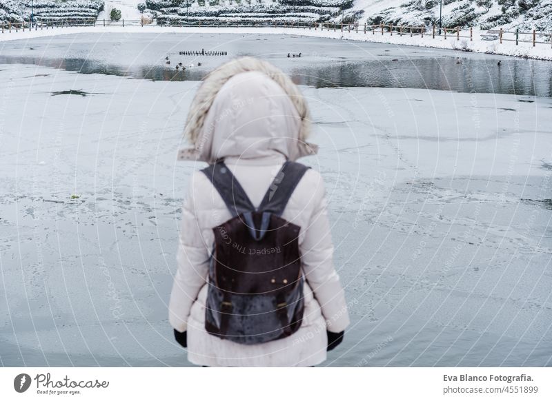 back view of backpacker woman standing in front of frozen lake in city. Lifestyle during winter in city frost pier snow dock caucasian 30s outdoors urban alone
