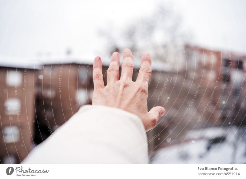 unrecognizable woman hand touching snow flakes during winter in city, neighborhood background. winter lifestyle in city snowing caucasian happy urban smiling