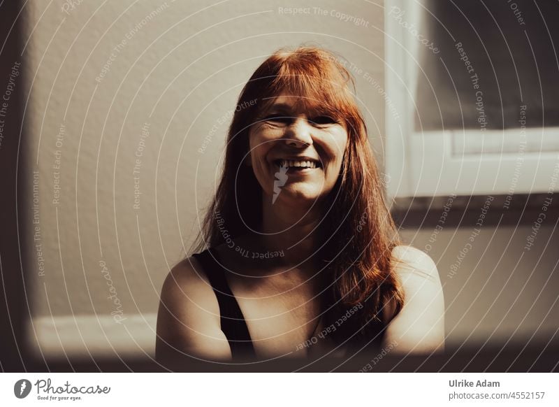 A new day begins - woman with red long hair laughs and looks forward to the new day Optimism Looking into the camera Authentic Friendliness Sympathy Contentment