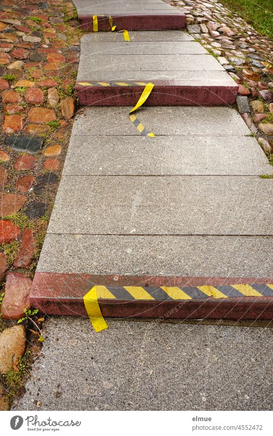 a stone path lined with natural stones, consisting of large slabs and built-in steps, from which the yellow-black marking band is detached / ascent / ground marking