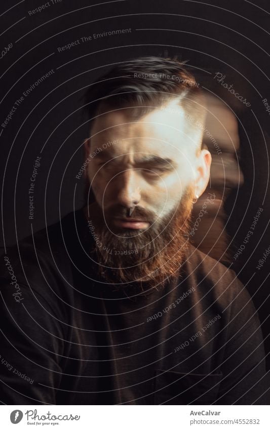 Cinematic shot of a young hipster bearded man with long exposure with cinematic lighting. Attractive man looking serious straight to camera, mental health concept. Depression and anxiety portrait