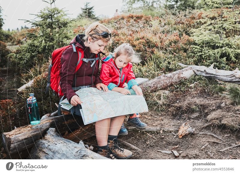 Family trip in mountains. Mother and her little daughter examining a map, sitting on stump during trip family child vacation summer hike travel journey active