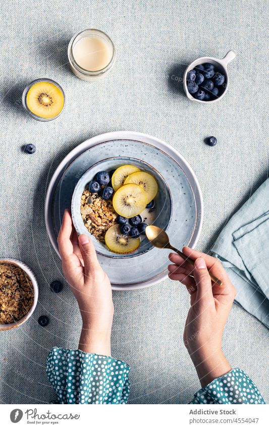 Woman with bowl of granola for breakfast woman kiwi morning blueberry healthy food female muesli meal homemade delicious fruit table vitamin tasty super food