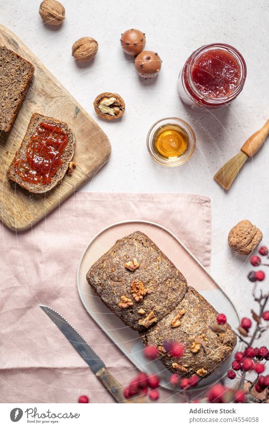 Loaf of baked bread with jam and honey grain loaf cut homemade walnut composition knife seed piece jar sweet food table napkin tasty wholegrain nutrition