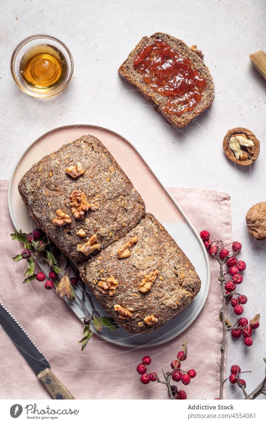 Loaf of baked bread with jam and honey grain loaf cut homemade walnut composition knife seed piece jar sweet food table napkin tasty wholegrain nutrition