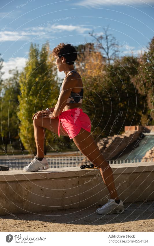 Athletic young Hispanic lady stretching legs in park sportswoman warm up workout wellness exercise training vitality energy fitness female ethnic hispanic