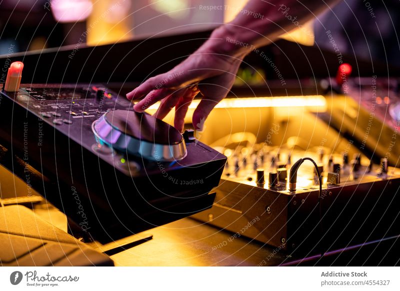 Crop DJ mixing music at counter in club man turntable dj nightclub party sound mixer perform audio festive entertain nightlife male hand controller console