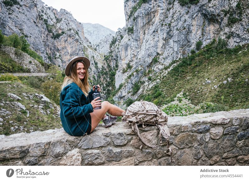 Woman drinking water from bottle on stony border in mountains woman thirst highland landscape hike slope freedom female journey trekking hiker adventure rock