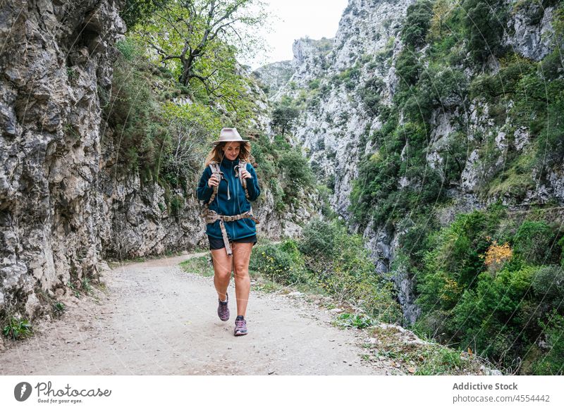 Young woman walking along path in mountainous terrain backpacker explore trekking highland slope range steep discovery female environment pathway ridge tourism